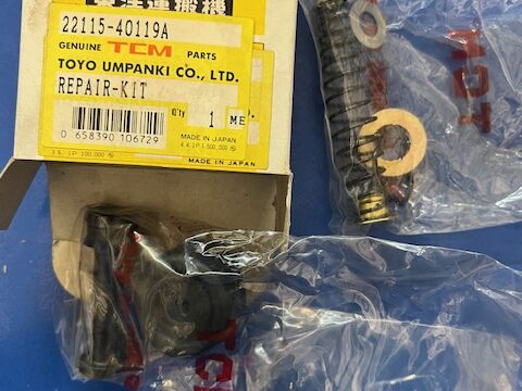 TCM repair kit box with yellow label and clear plastic bags containing mechanical parts on a blue surface