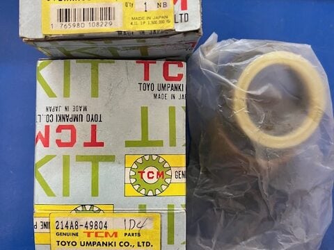 Two boxes labeled KIT from Toyo Umpanki Co., Ltd., indicating an overhaul kit for the left cylinder, with a sealed yellow gasket in a plastic bag.